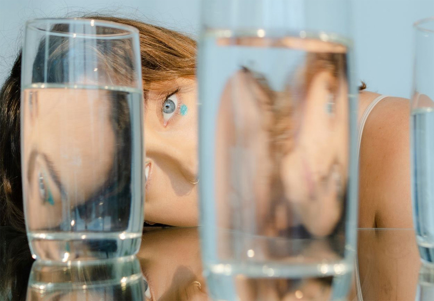 Artistic view of woman's hair and eye through filled glasses
